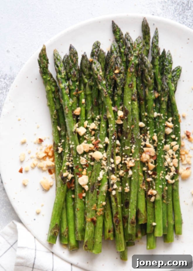 Cooked asparagus being transferred to a serving dish, ready to be topped with dressing and peanuts.