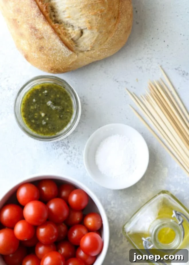 Charred Pesto Bruschetta Skewers 3 Fresh ingredients for grilled bruschetta skewers including bread, tomatoes, olive oil, and pesto.