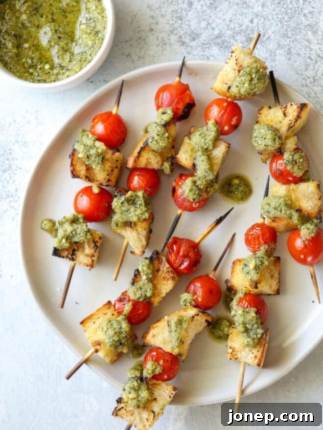Charred Pesto Bruschetta Skewers 5 Close-up of grilled bruschetta skewers with pesto drizzle on a serving platter.