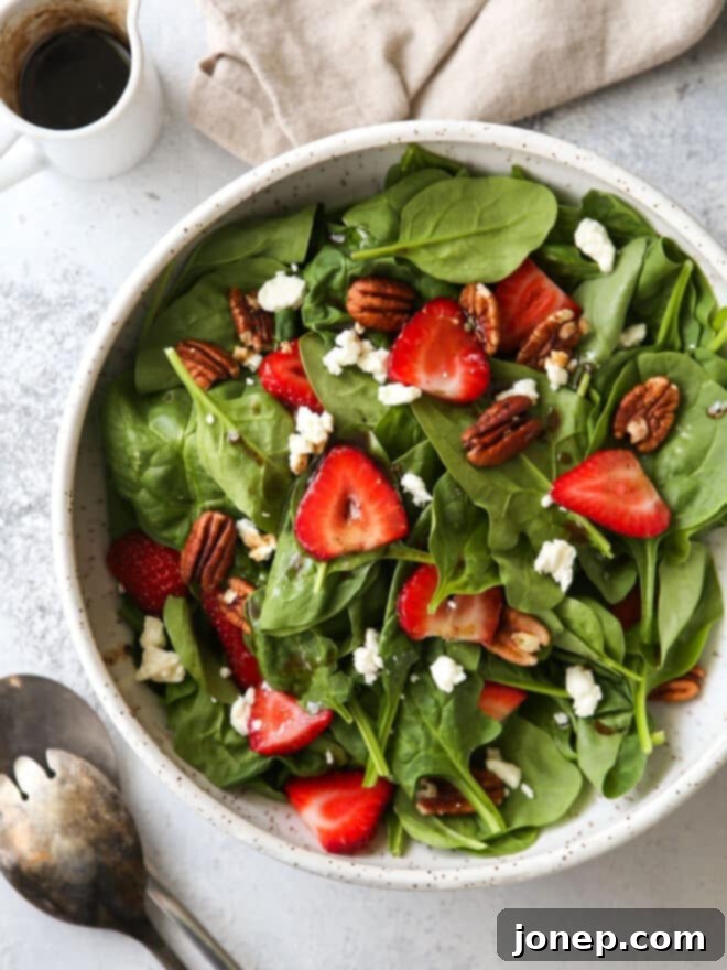 Warm Brown Butter Strawberry Spinach Salad 6 view of bowl of strawberry spinach salad with salad tongs