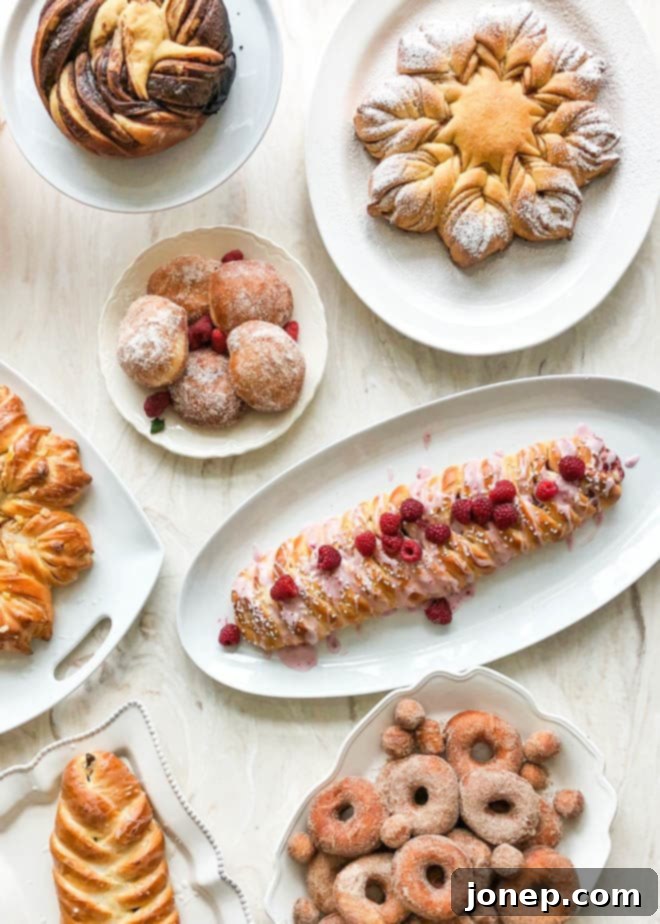 A table full of various freshly baked breads, pastries, and doughnuts