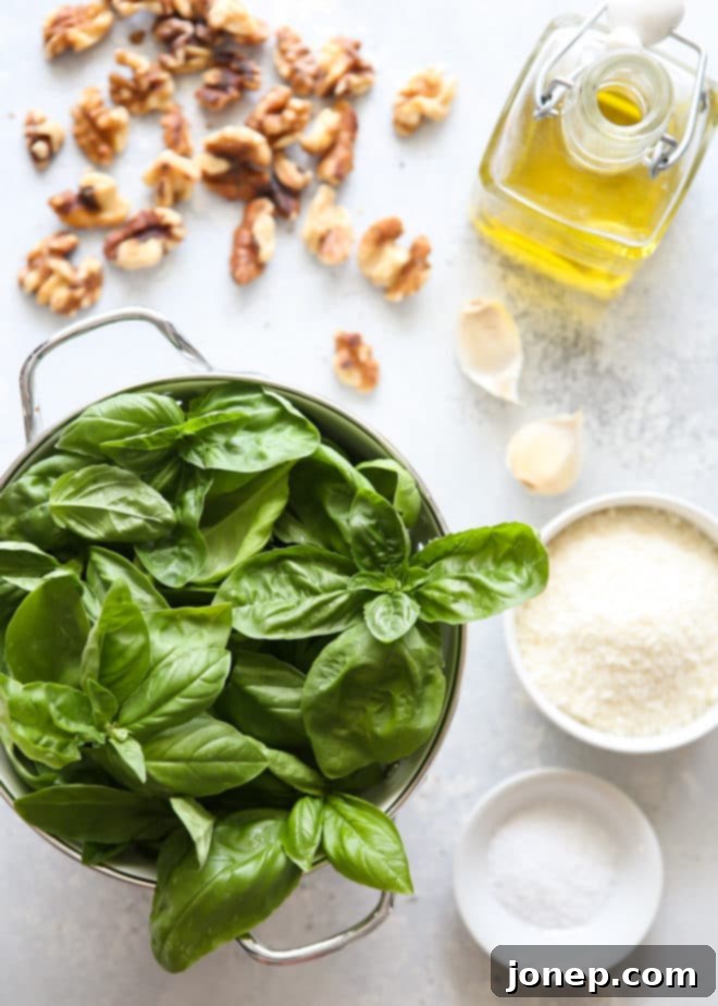 Ingredients laid out for making basil walnut pesto, including basil, walnuts, cheese, garlic, and olive oil.