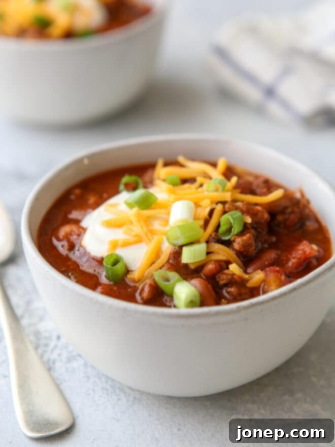 Effortless Weeknight Chili 3 Close-up of a bowl of homemade chili topped with sour cream, shredded cheese, and fresh green onions
