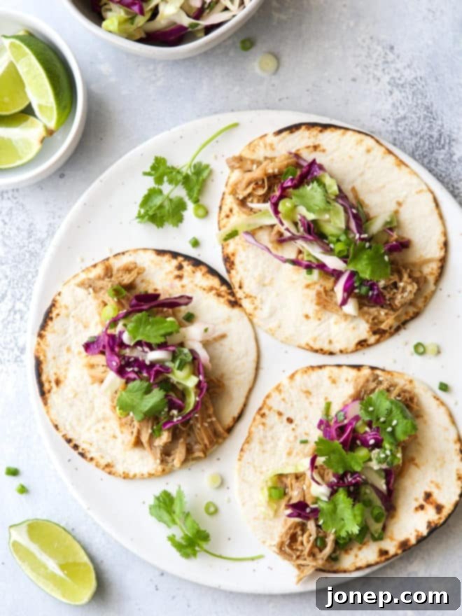 Gochujang Pulled Pork Tacos 2 Three Slow Cooker Korean Pork Tacos with fresh slaw on a white plate, ready to be enjoyed.