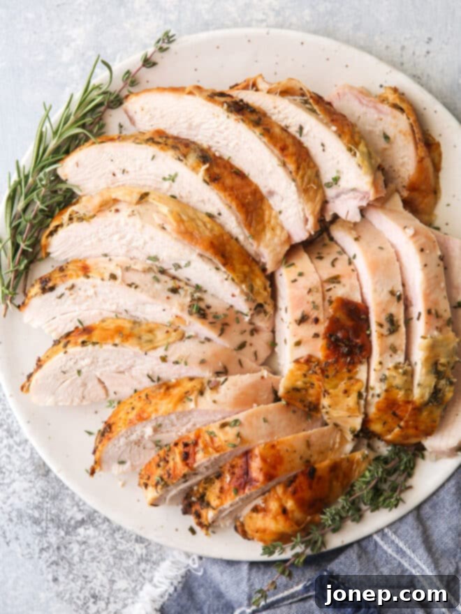 Aromatic Herb Roasted Turkey Breast 3 sliced turkey breast on a plate with herbs