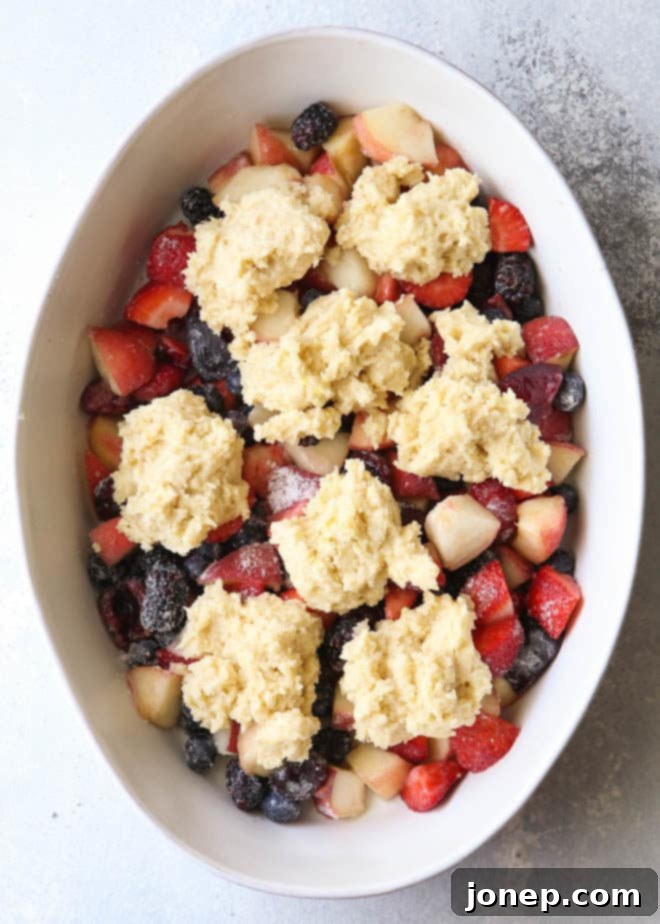 Close-up of the fruit filling for the cobbler, with sliced peaches, plums, cherries, and berries glistening before baking.