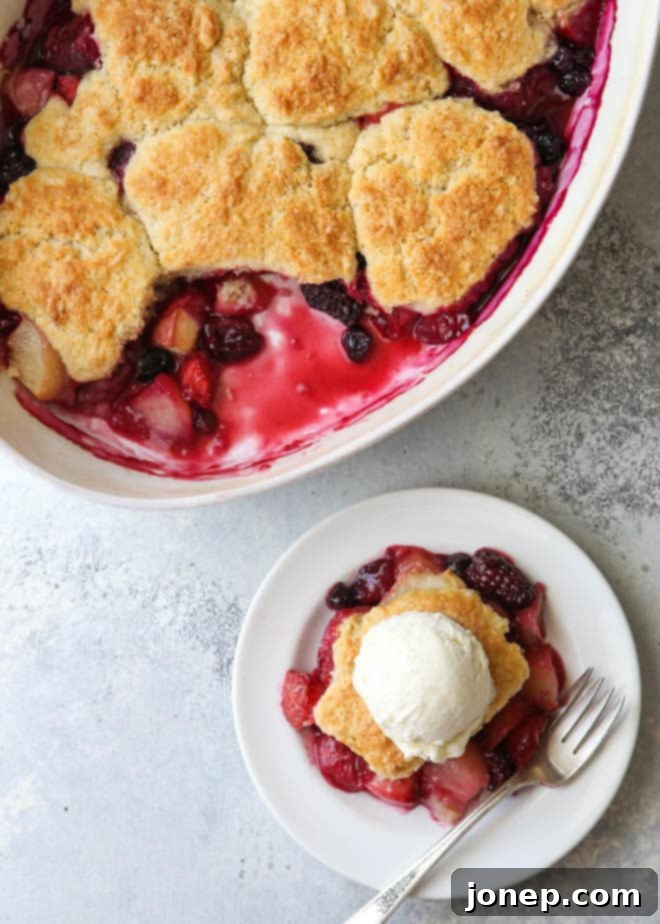 A spoonful of the homemade buttermilk cobbler topping batter being dropped onto the fresh fruit filling before baking.