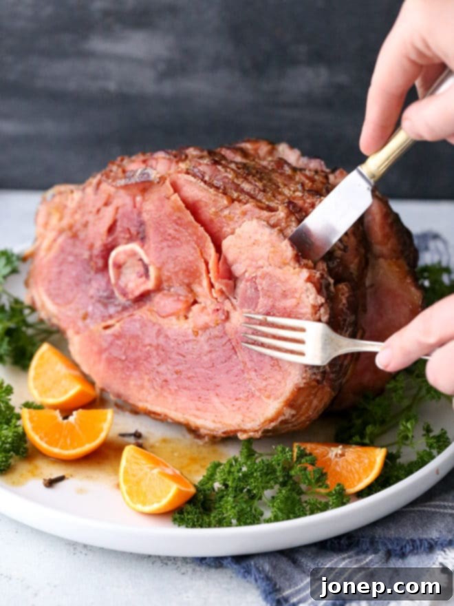 Close-up shot of a spiral ham being glazed with the homemade citrus spice mixture, showing the rich, glossy texture of the glaze.
