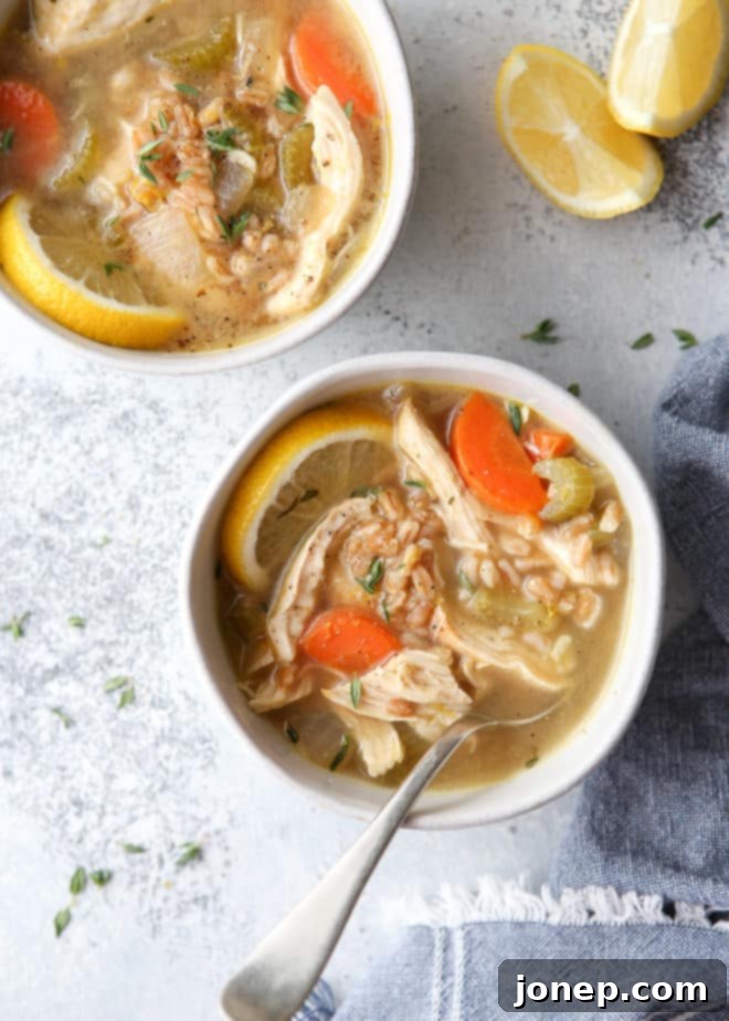 A bowl of delicious lemon, chicken, and farro soup on a wooden table, ready to be enjoyed