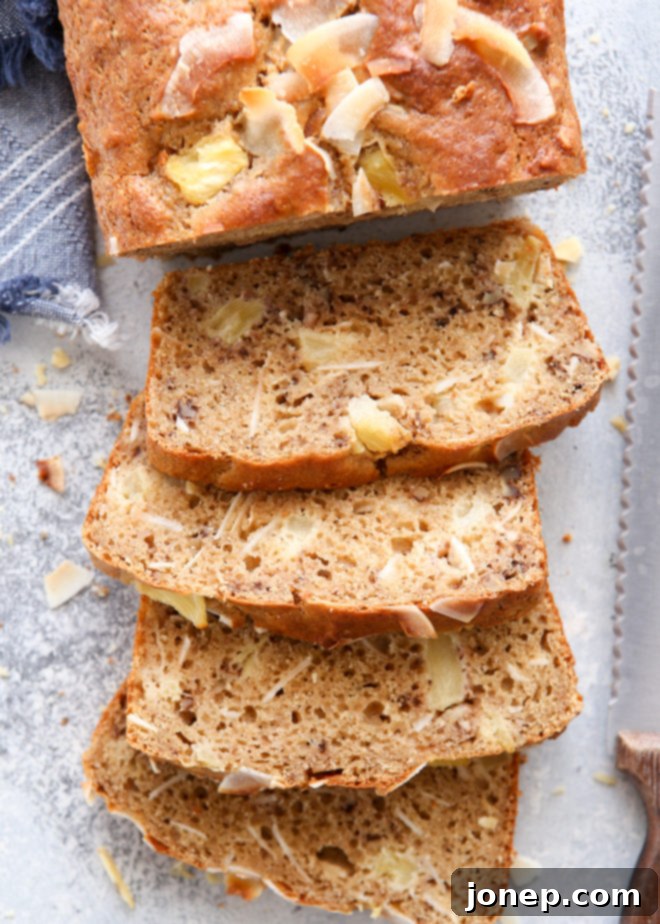 This pineapple coconut bread is So flavorful and a little bit better for you! A perfectly sliced loaf showcasing the moist interior.