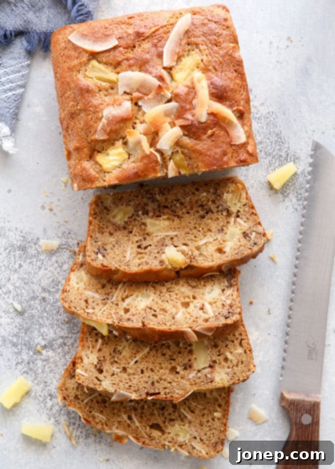 A slice of moist pineapple coconut bread on a plate, showing the texture and fruit pieces.