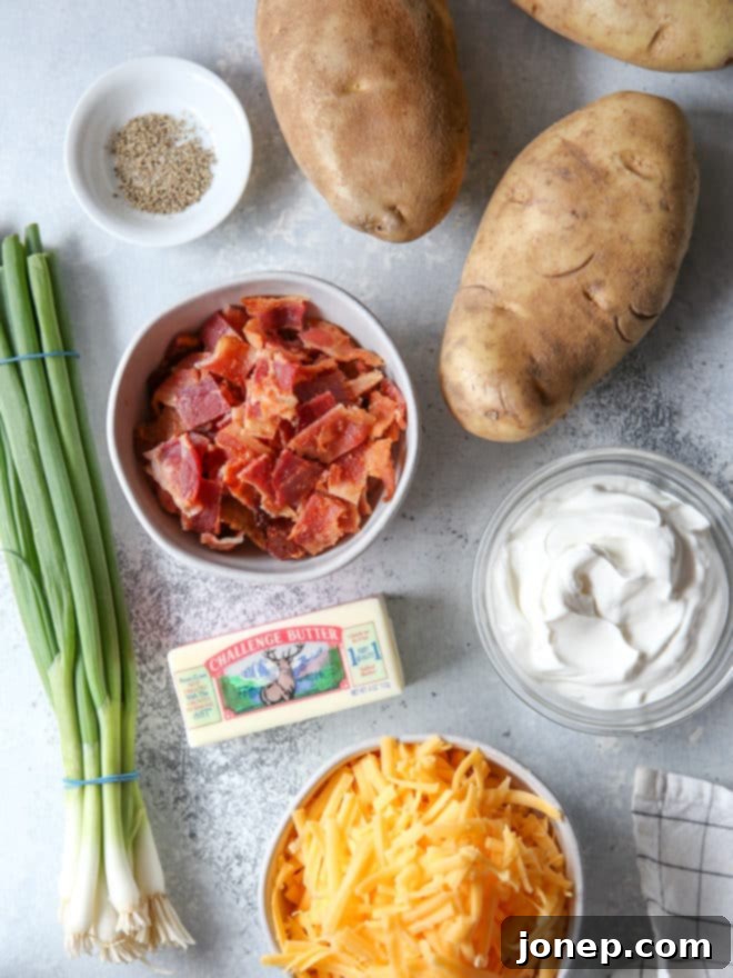 A collection of fresh ingredients laid out on a kitchen counter, ready to be prepared for loaded baked potato bites, including russet potatoes, cheddar cheese, bacon, sour cream, and green onions.