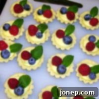 Mini Lemon Curd Tarts 2 Close-up of a single mini lemon curd tart with berries and mint