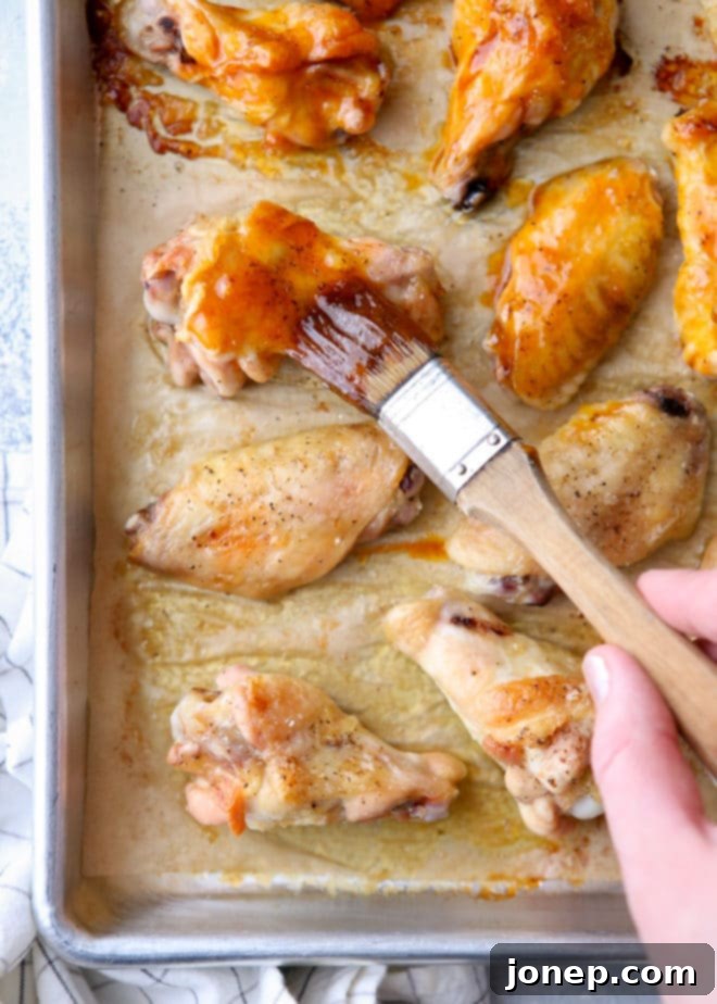 A close-up of crispy, glazed chicken wings on a baking sheet, ready to be served.