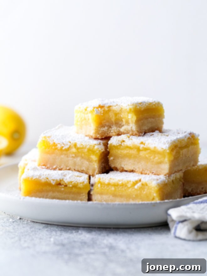 Freshly baked classic lemon bars with a golden shortbread crust, smooth lemon filling, and powdered sugar on top.