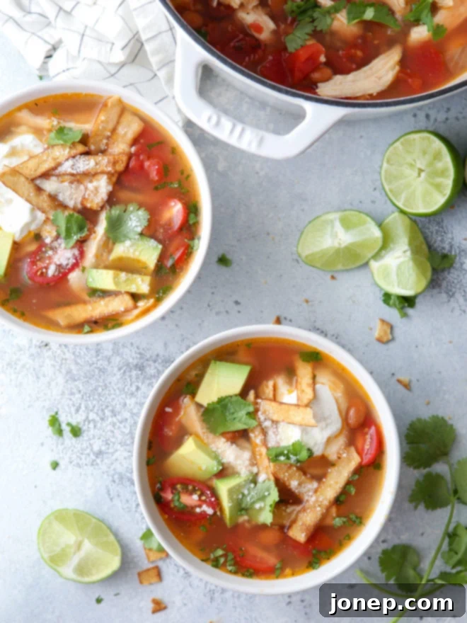 A steaming bowl of easy homemade chicken tortilla soup, garnished with avocado, cilantro, and tortilla strips.