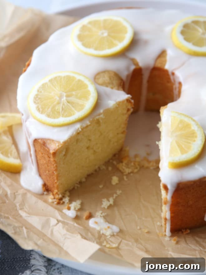The full Lemon Cream Cheese Pound Cake cooling on a wire rack, covered in its glistening lemon glaze, ready to be sliced and served.