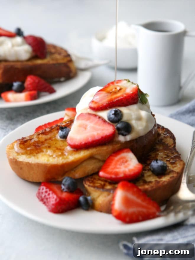 A close-up overhead shot of a perfectly cooked, golden-brown French toast slice, still warm on a griddle, with a small pat of butter melting on top, indicating readiness to serve.