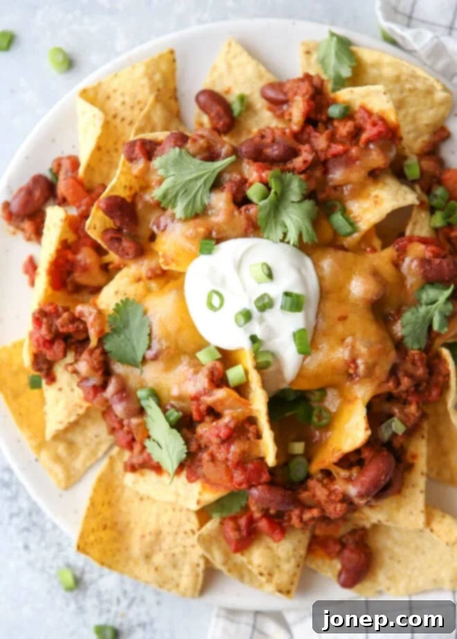 Ultimate Chili Cheese Nachos 2 Closeup of a vibrant plate of chili cheese nachos, showcasing melted cheese, rich chili, and fresh toppings