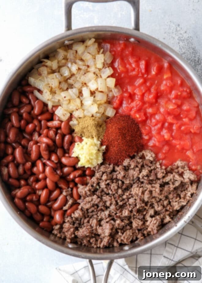 Ultimate Chili Cheese Nachos 4 Ingredients for easy homemade chili simmering in a pot, including ground beef, beans, and tomatoes
