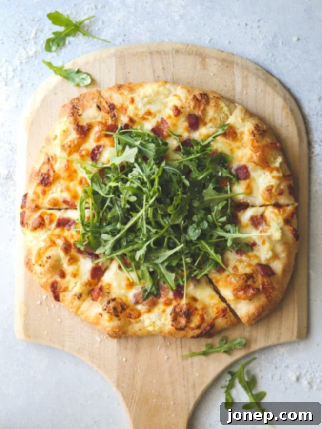 This simple but irresistible three-cheese white pizza is topped with crispy bacon and fresh arugula for maximum flavor.