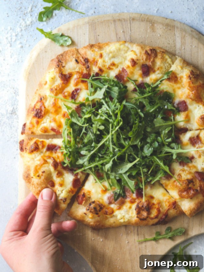 This simple but irresistible three-cheese white pizza is topped with crispy bacon and fresh arugula for maximum flavor.