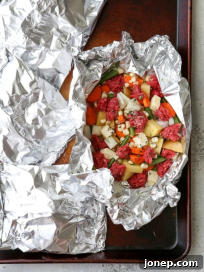 A freshly cooked beef and veggie tin foil dinner, opened to reveal tender meat and vegetables, ready to be enjoyed.