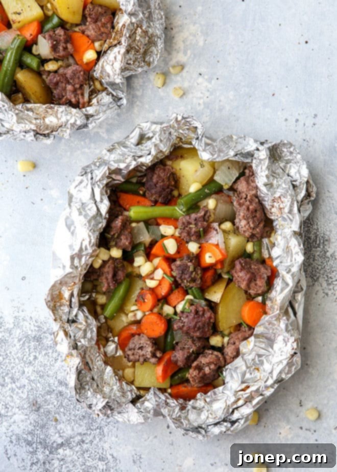 A hand holding an opened foil dinner packet filled with cooked beef, potatoes, carrots, and corn, ready to eat.