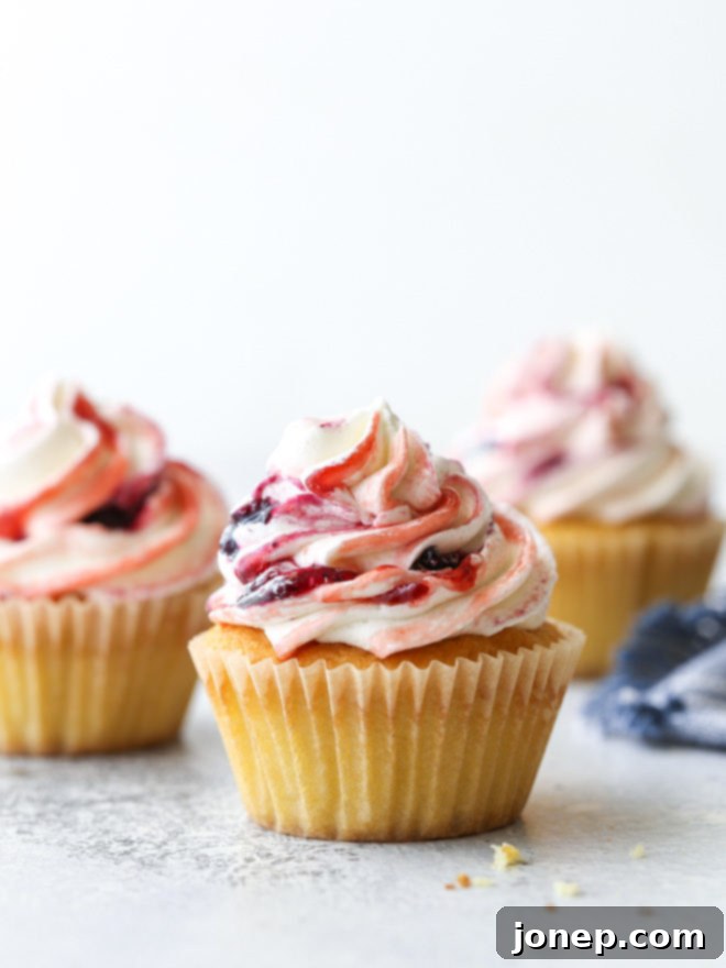 Delicate vanilla cupcakes topped with buttercream frosting swirled with berry preserves are lovely and delicious!
