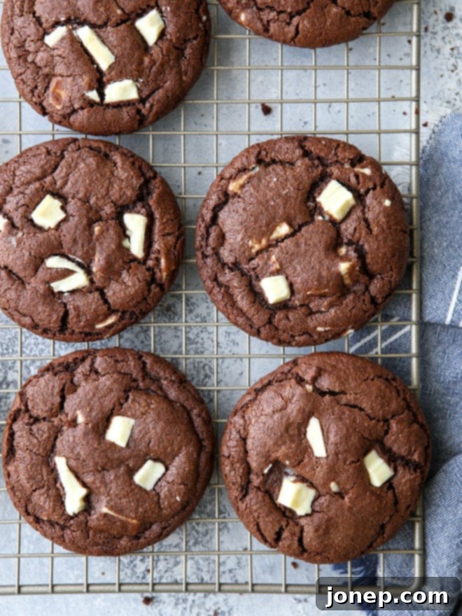 A close-up of the perfectly baked chocolate white chocolate chunk cookies on a cooling rack, showcasing their soft texture and melted chunks.