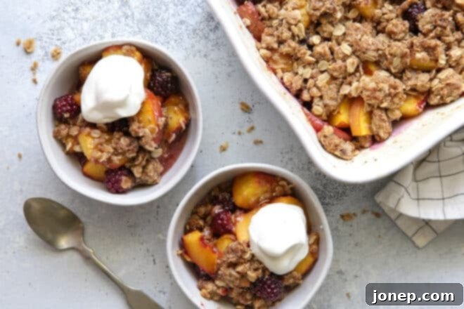 blackberry peach crisp in bowls with whipped cream and a spoon