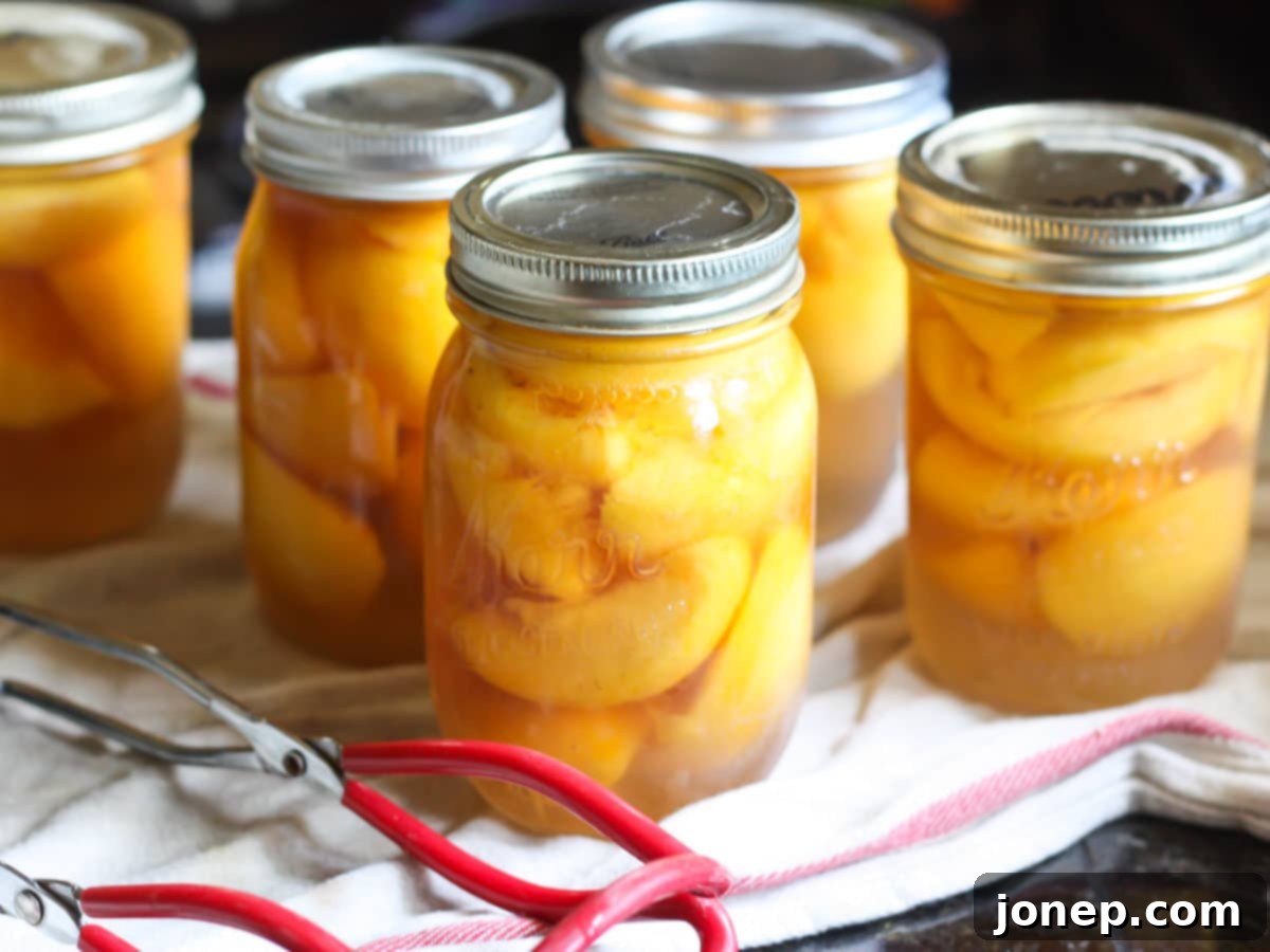 Beautifully sealed jars of homemade canned peaches cooling on a towel