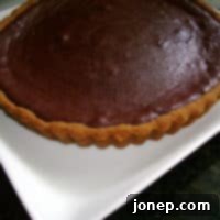 Rich Dark Chocolate Tart with Spiced Gingersnap Crust 2 Close-up of a dark chocolate tart slice on a white plate