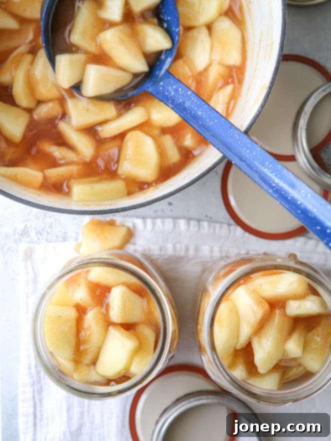 Ladle the warm apple pie filling carefully into sterilized canning jars, ensuring proper headspace.