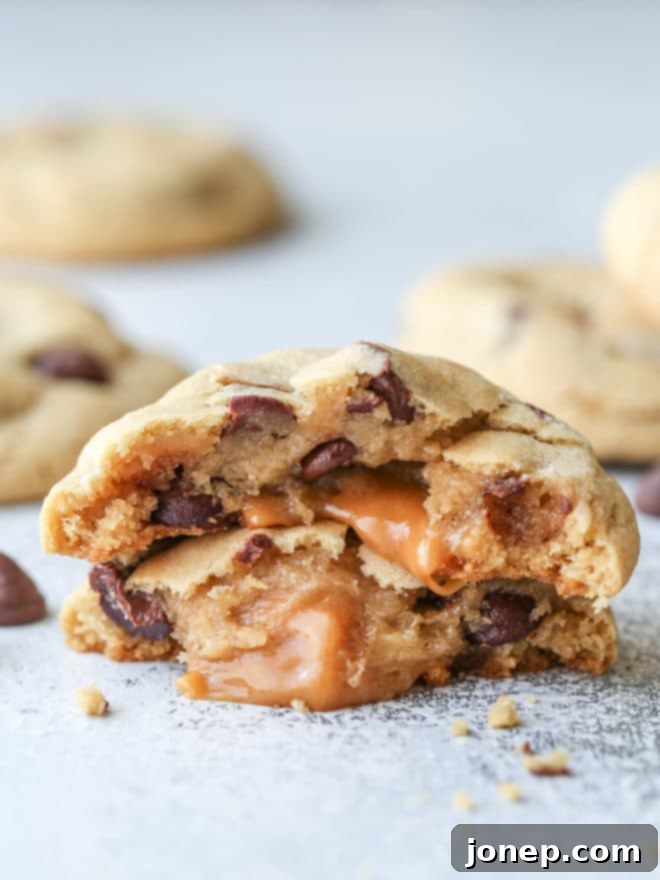 Close-up of a warm chocolate chip cookie revealing a luscious, gooey caramel center