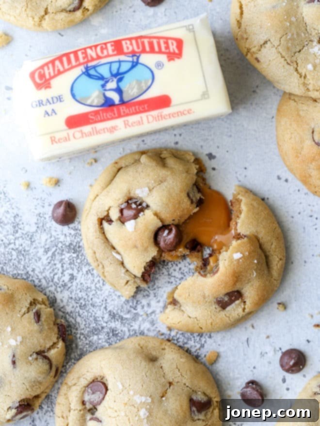 A stack of perfectly baked caramel stuffed chocolate chip cookies, glistening with sea salt