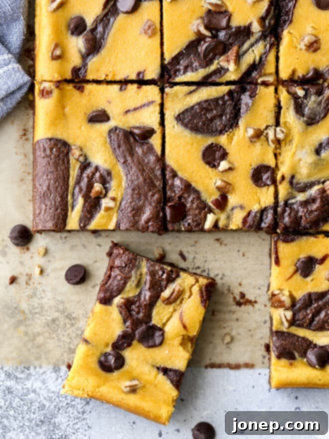Sliced pumpkin cheesecake swirl brownies showing distinct layers and swirled patterns, ready for serving