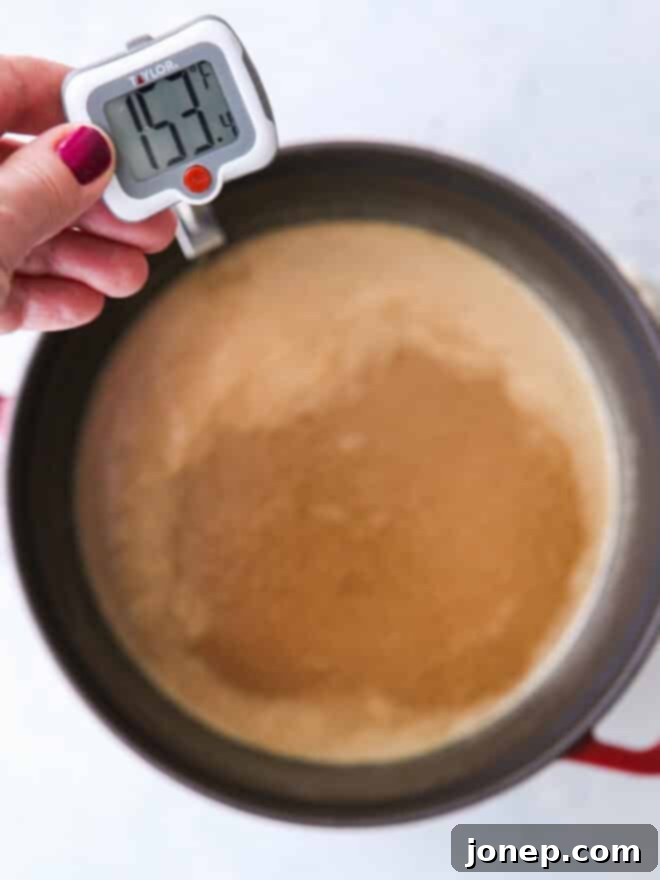 Golden Penuche Brown Sugar Fudge 4 close up of sugar mixture cooking in a pot with a candy thermometer showing 238°F