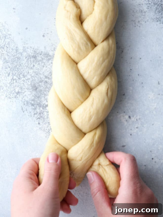 Hands braiding egg bread dough into a beautiful loaf