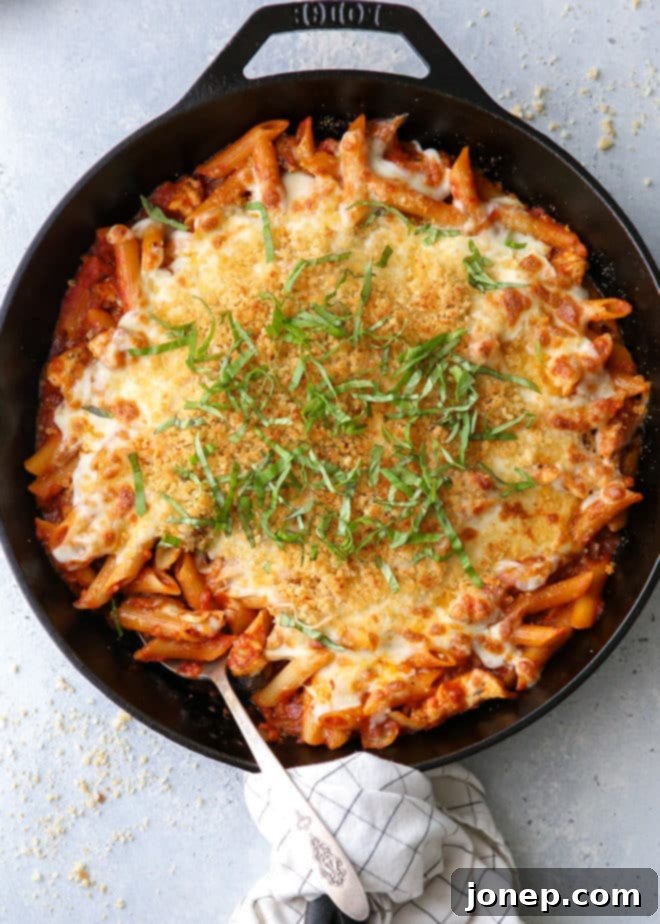 A close-up of the finished chicken parmesan pasta skillet, showing melted cheese and toasted breadcrumbs.