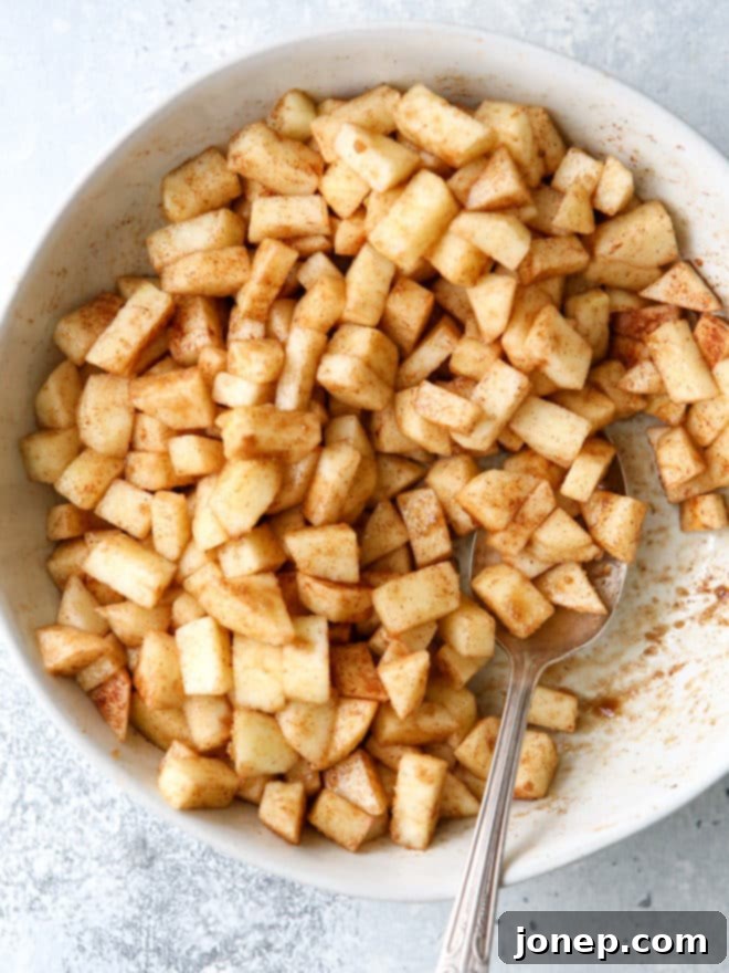 Finely chopped cinnamon scented apples, perfectly seasoned with brown sugar and cinnamon, ready for the caramel apple cheesecake bar filling.