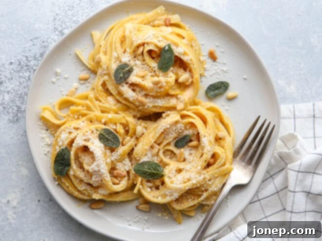 plated pumpkin alfredo pasta with garnishes on a plate with fork