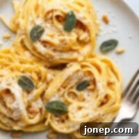 plated pumpkin alfredo pasta with garnishes on a plate with fork