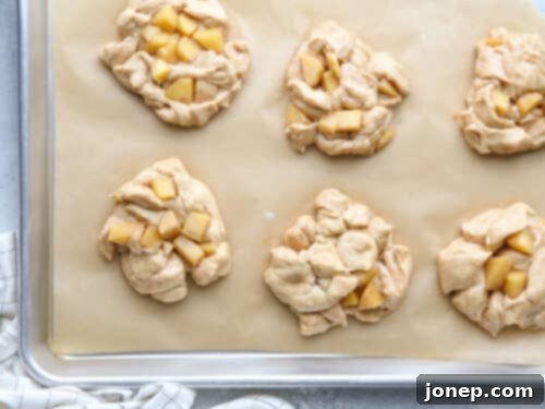 Shaped apple fritters on parchment paper, ready for their second rise