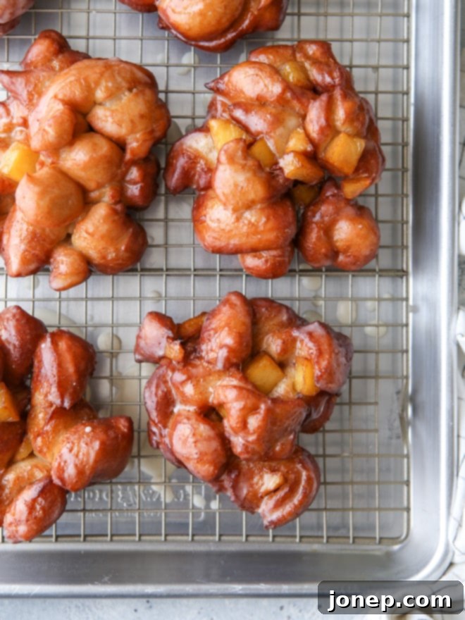 Freshly made homemade apple fritters with maple glaze, stacked on a plate and ready to be enjoyed as a fall treat