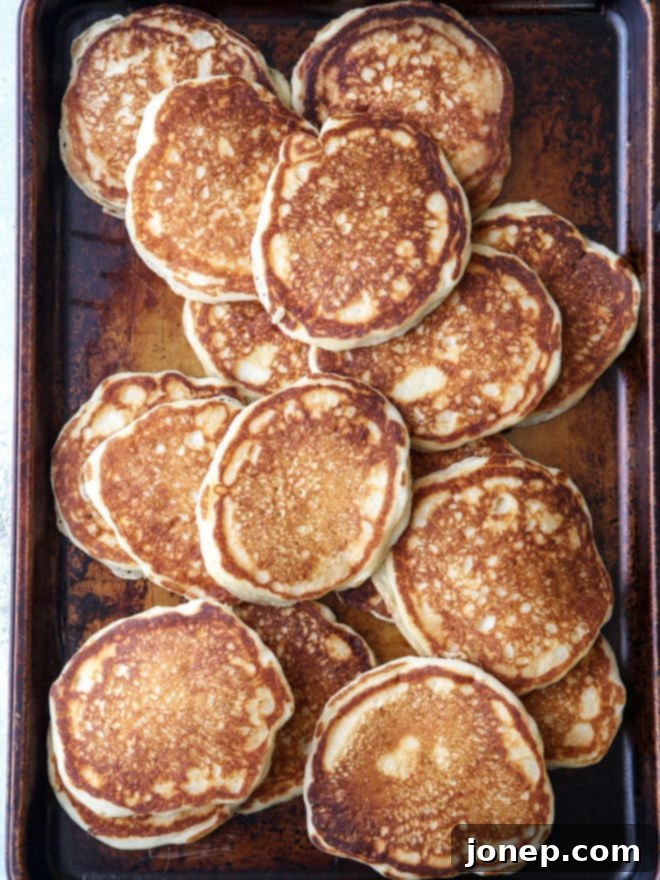 A close-up shot of perfectly cooked, fluffy buttermilk pancakes ready to be served on a breakfast board.