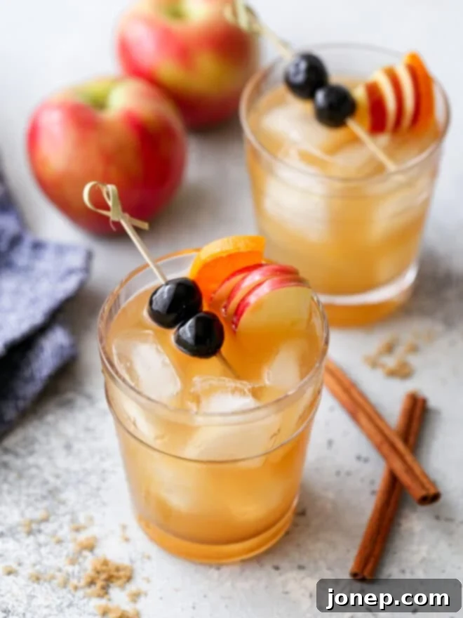 apple cider old fashioned in a glass, garnished with apple slices and a cinnamon stick