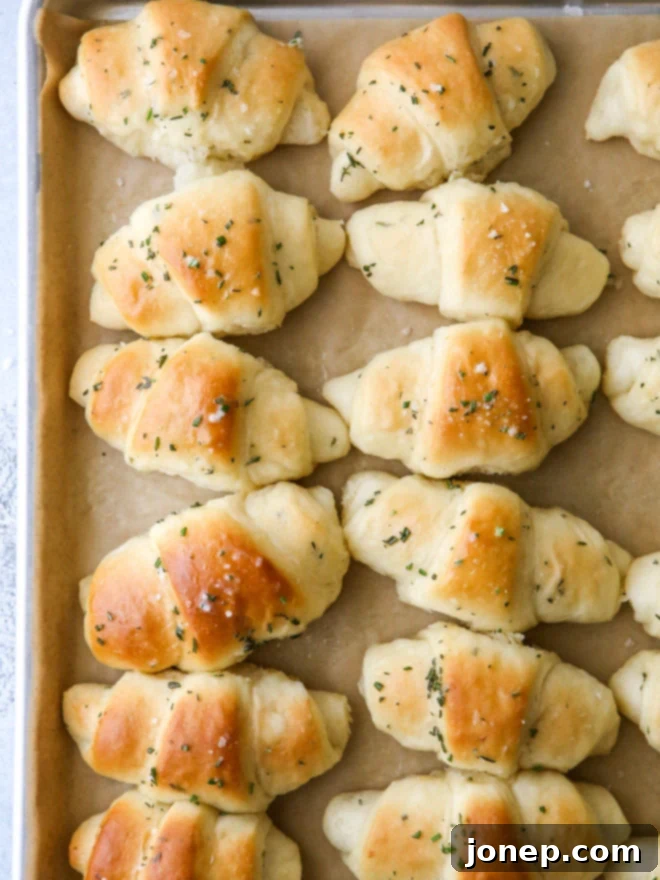Delicious golden brown garlic and herb crescent rolls, fresh from the oven, garnished with flaky salt