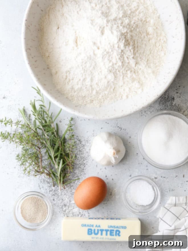 All the fresh ingredients laid out for making garlic and herb crescent rolls: flour, sugar, salt, yeast, egg, butter, water, minced garlic, rosemary, and thyme