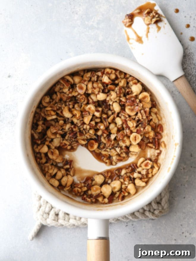 A close-up of the delicious mixed nut praline topping, glistening and ready for the pie.